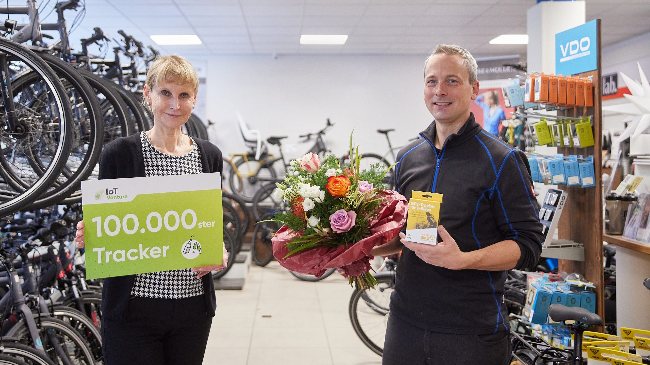 Foto, links eine Mitarbeiterin von IoT Venture mit einem Plakat Inder Hand, mir Aufschrift 