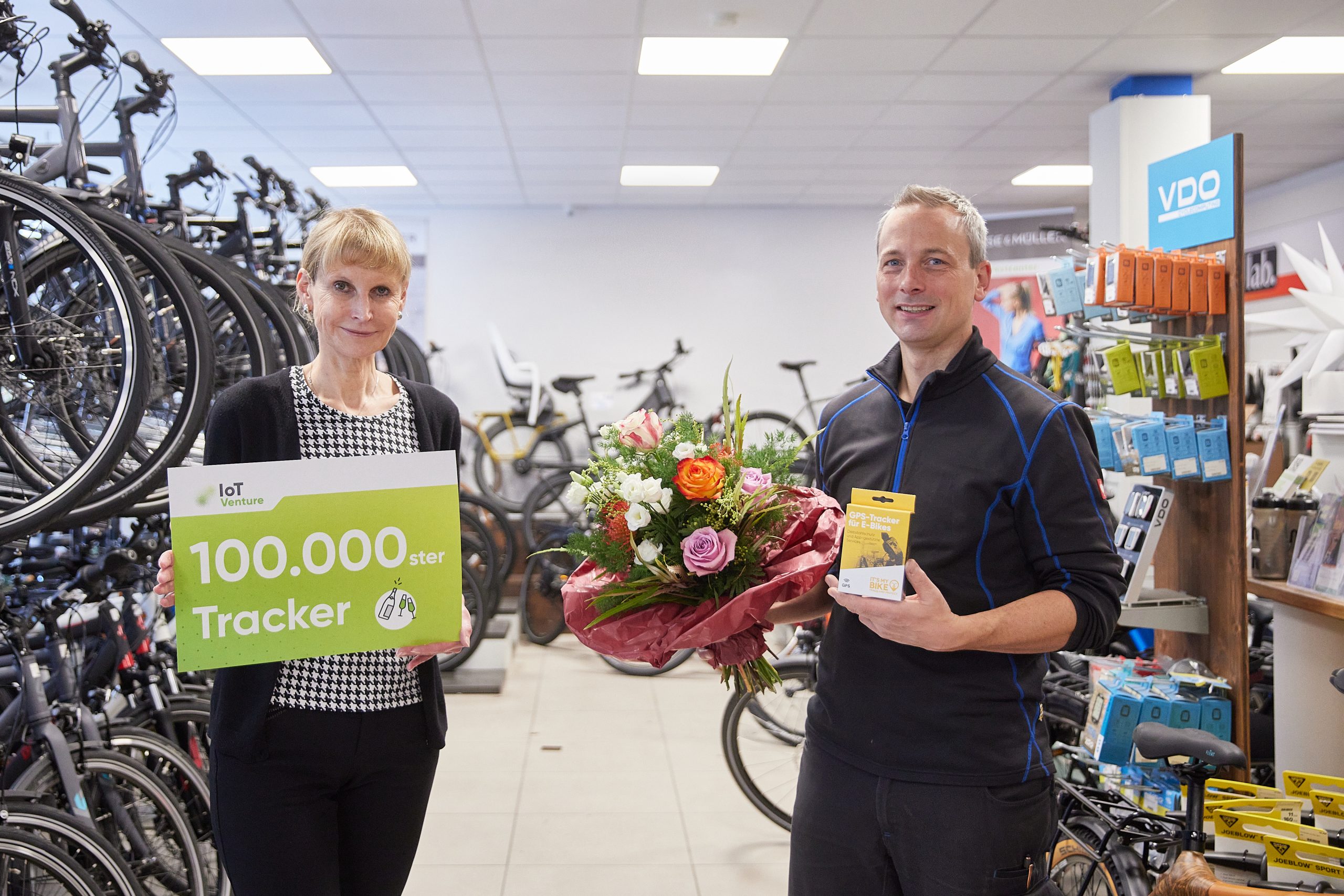 Foto, links eine Mitarbeiterin von IoT Venture mit einem Plakat Inder Hand, mir Aufschrift 