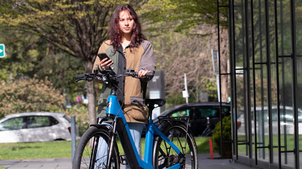 Frau auf E-Bike mit Handy in der Hand